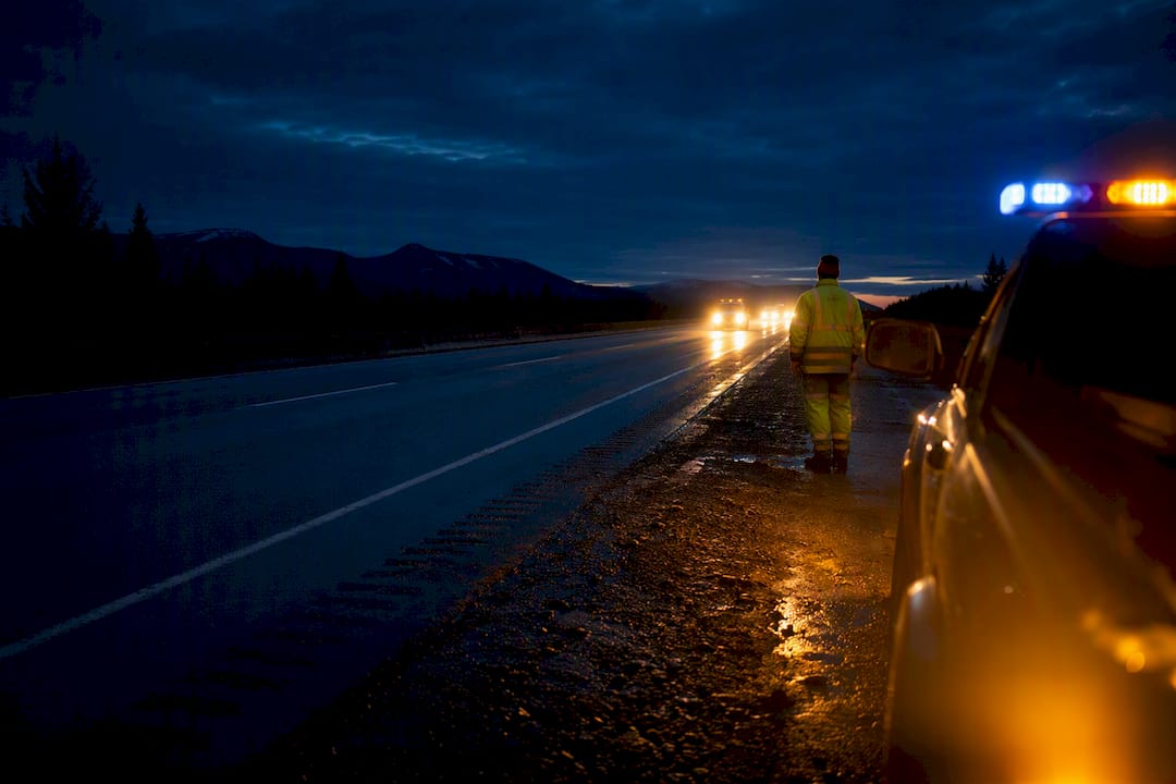 Roadside worker beside blue and amber warning lights