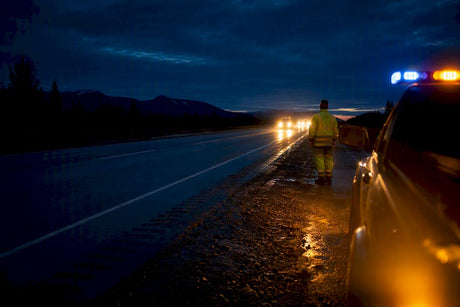 Roadside worker beside blue and amber warning lights