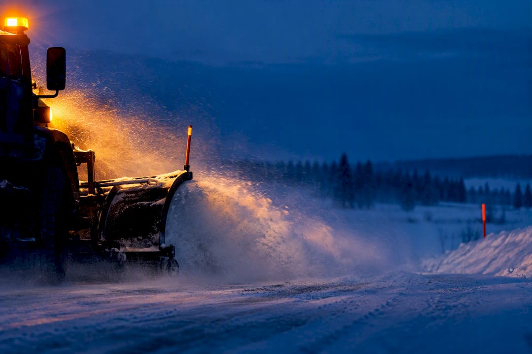 Snowplow warning lights cutting through blowing snow